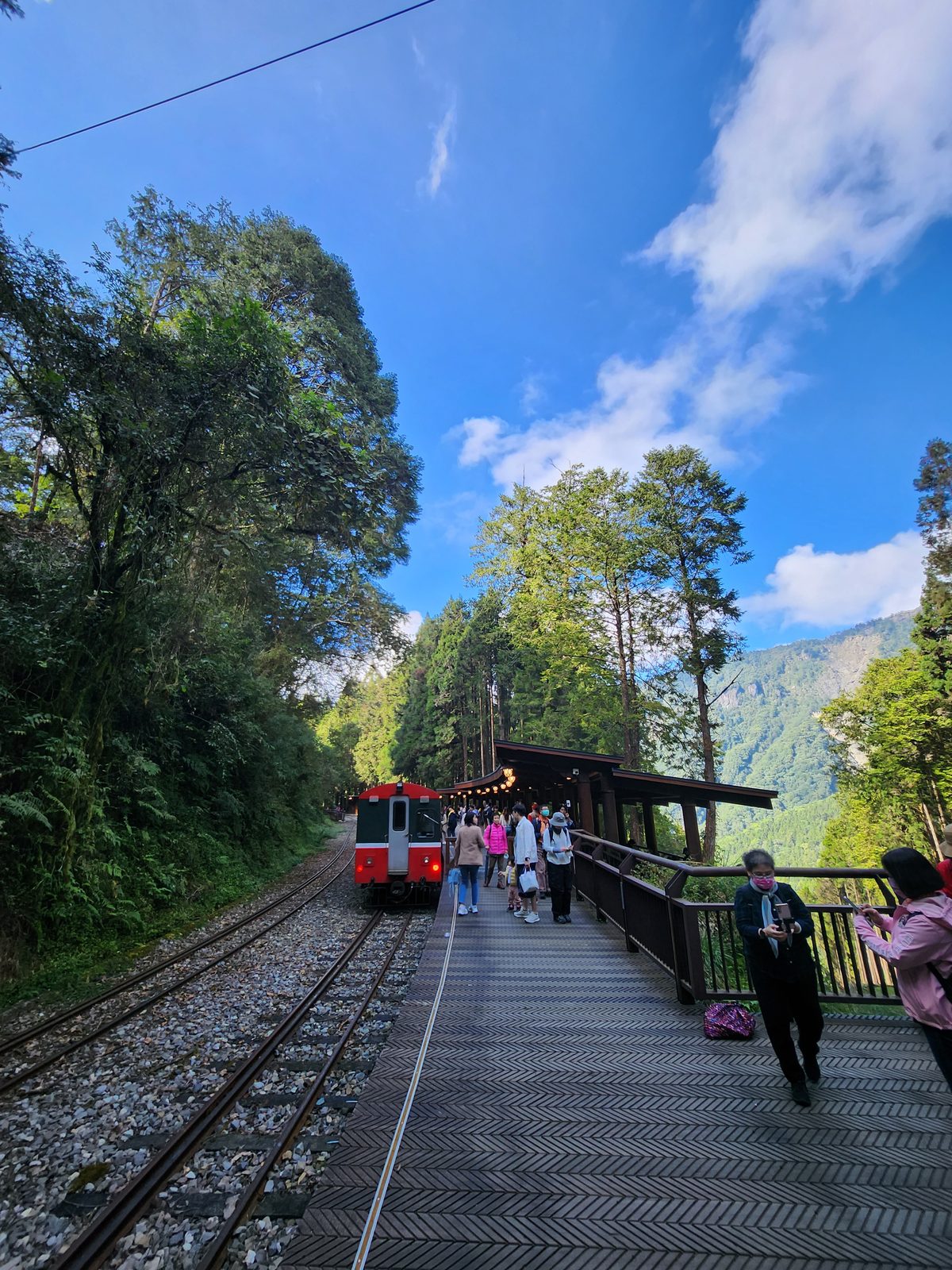 紅色列車車頭停在軌道盡頭,月台上有零星旅客