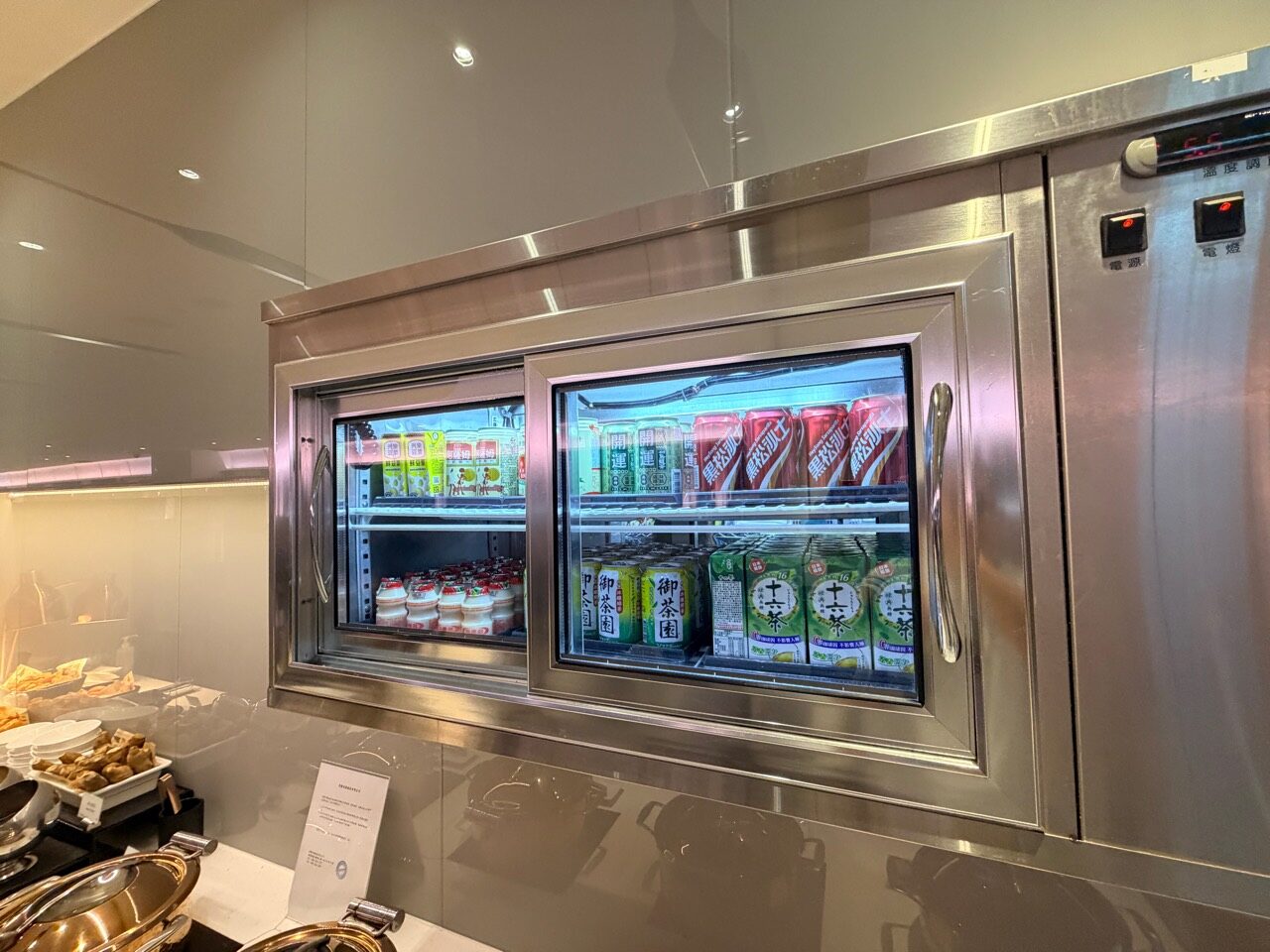 華航 D4 貴賓室冷藏櫃內分層擺放的啤酒、汽水、乳酸飲料與茶飲