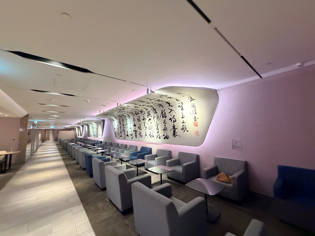 桃園機場第二航廈華航 D4 貴賓室內的長排單人沙發、茶几與發光書法牆