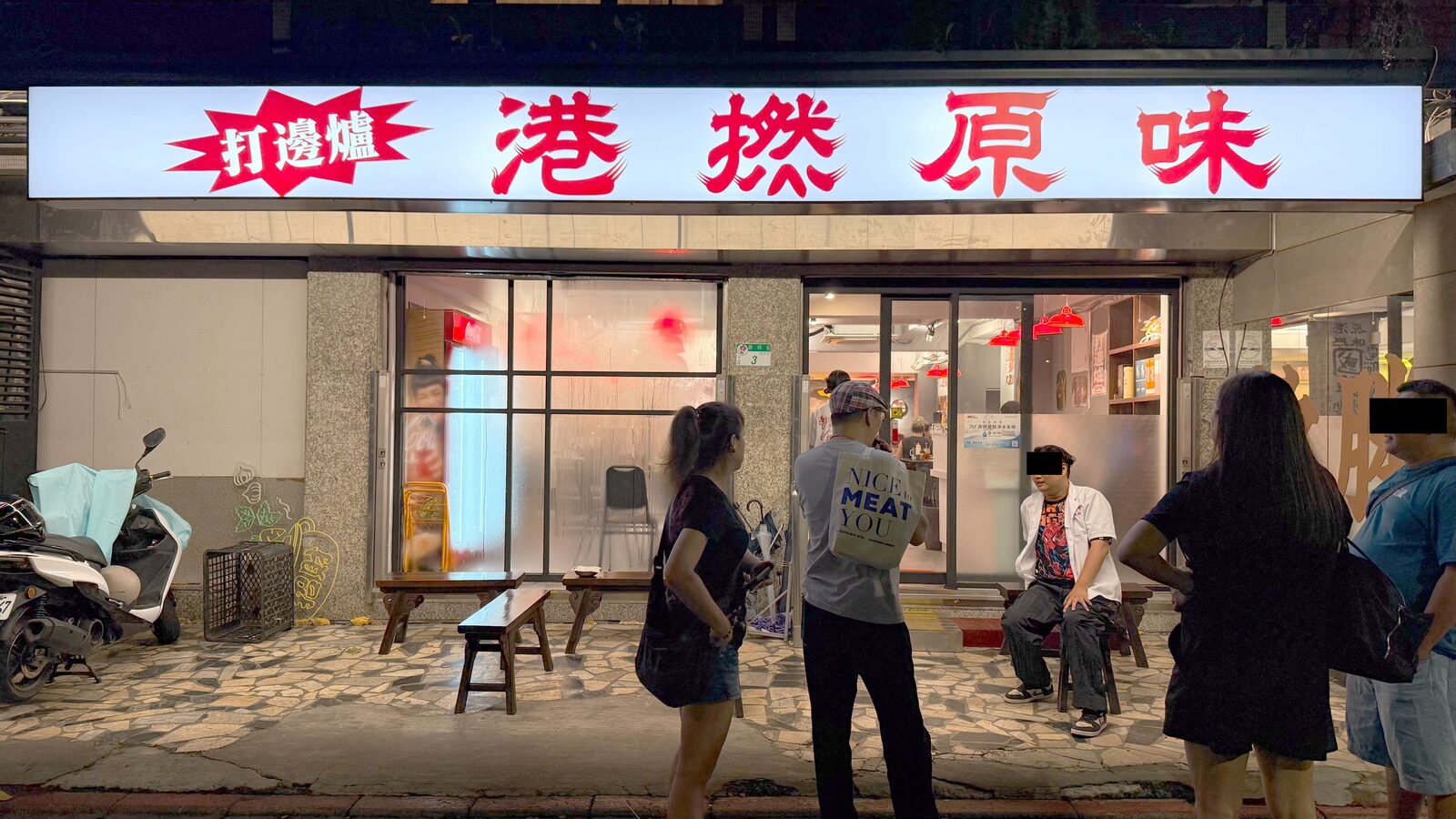 밤의 HK Hotpot 외관, 라이트박스 간판과 입구의 대기용 벤치
