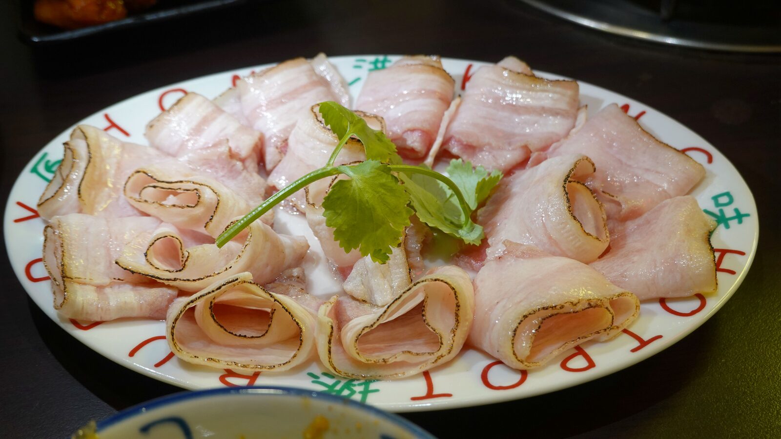 토치에 그을린 베이컨 돼지고기 슬라이스, 접시 테두리에 HOTPOT 글자