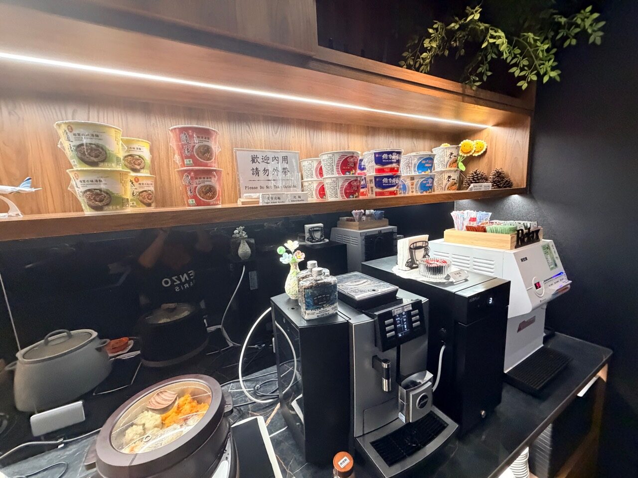 コーヒーマシンの上にはカップ麺があり、隣の掲示は店内利用と持ち出し禁止を案内しています。