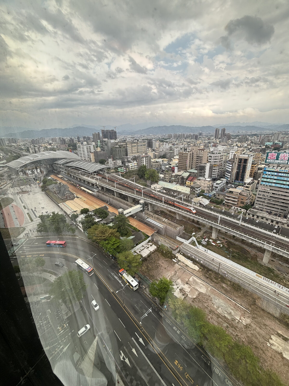 客房落地窗俯瞰台中車站高架鐵道與橘白列車