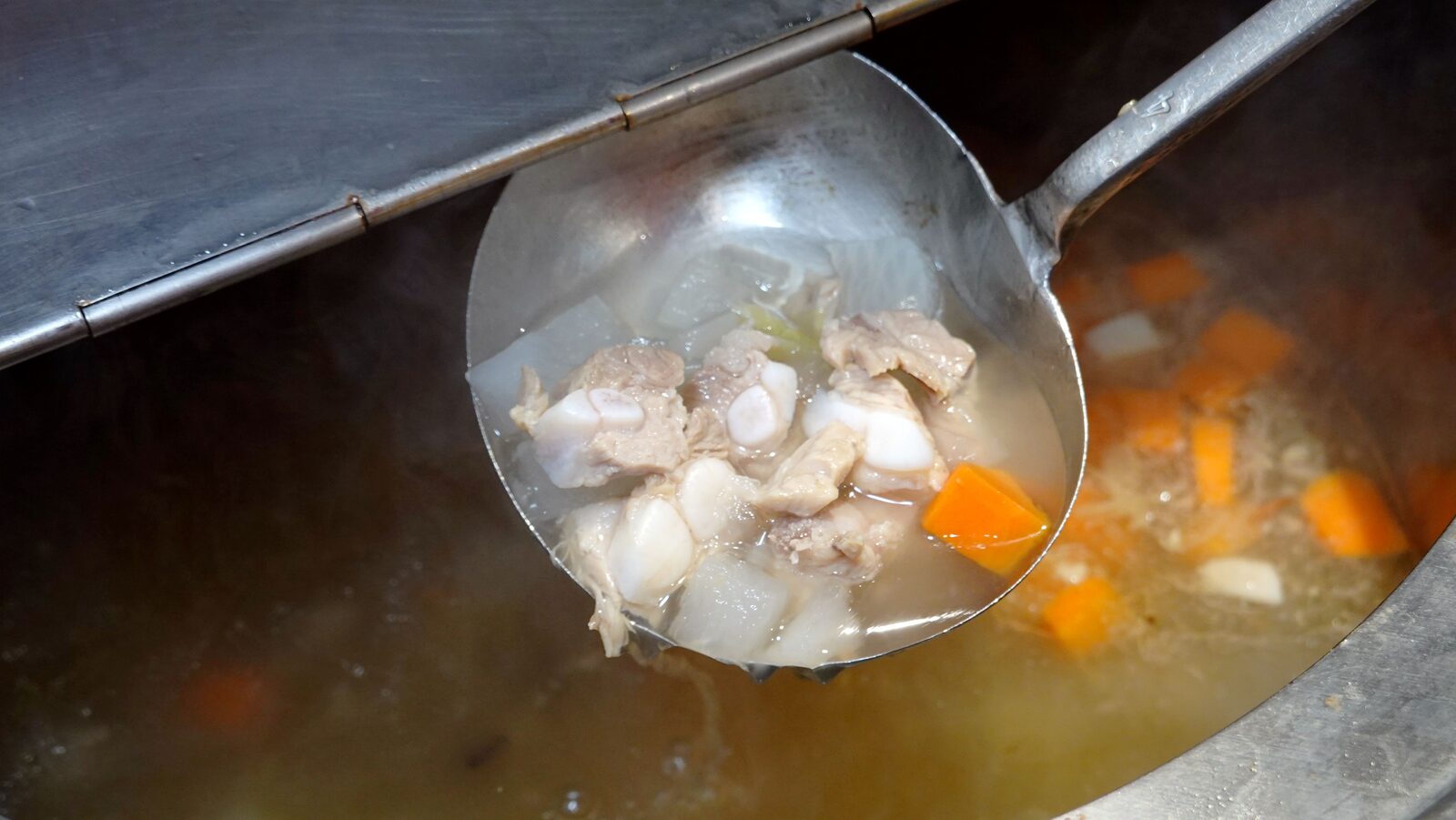 湯勺中的帶骨肉塊、白蘿蔔與紅蘿蔔