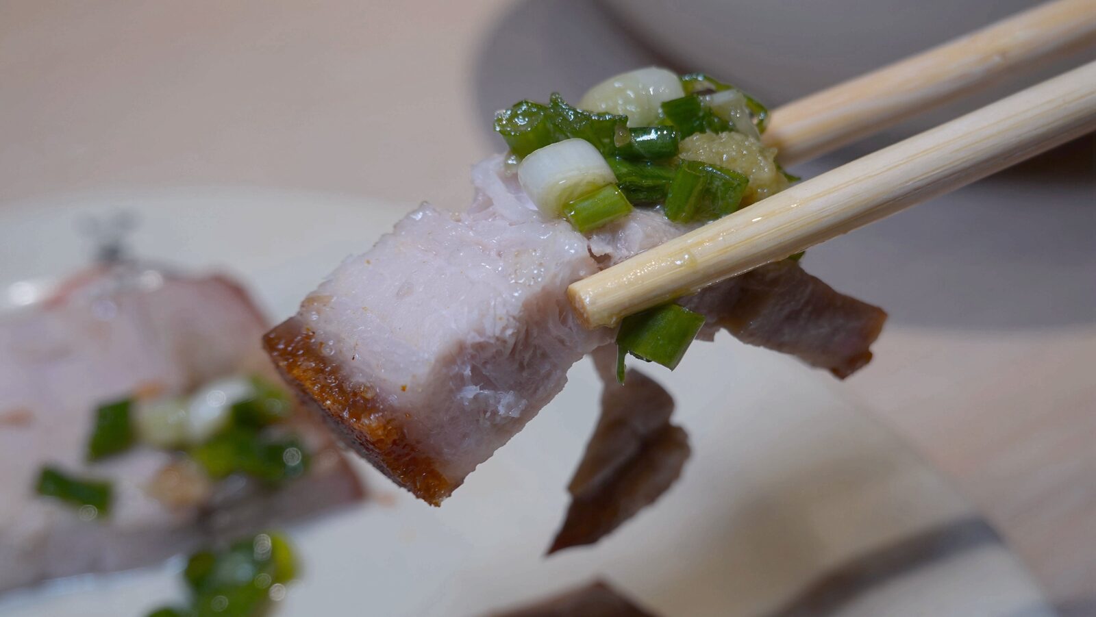 筷子夾起搭配蔥末的脆皮燒肉