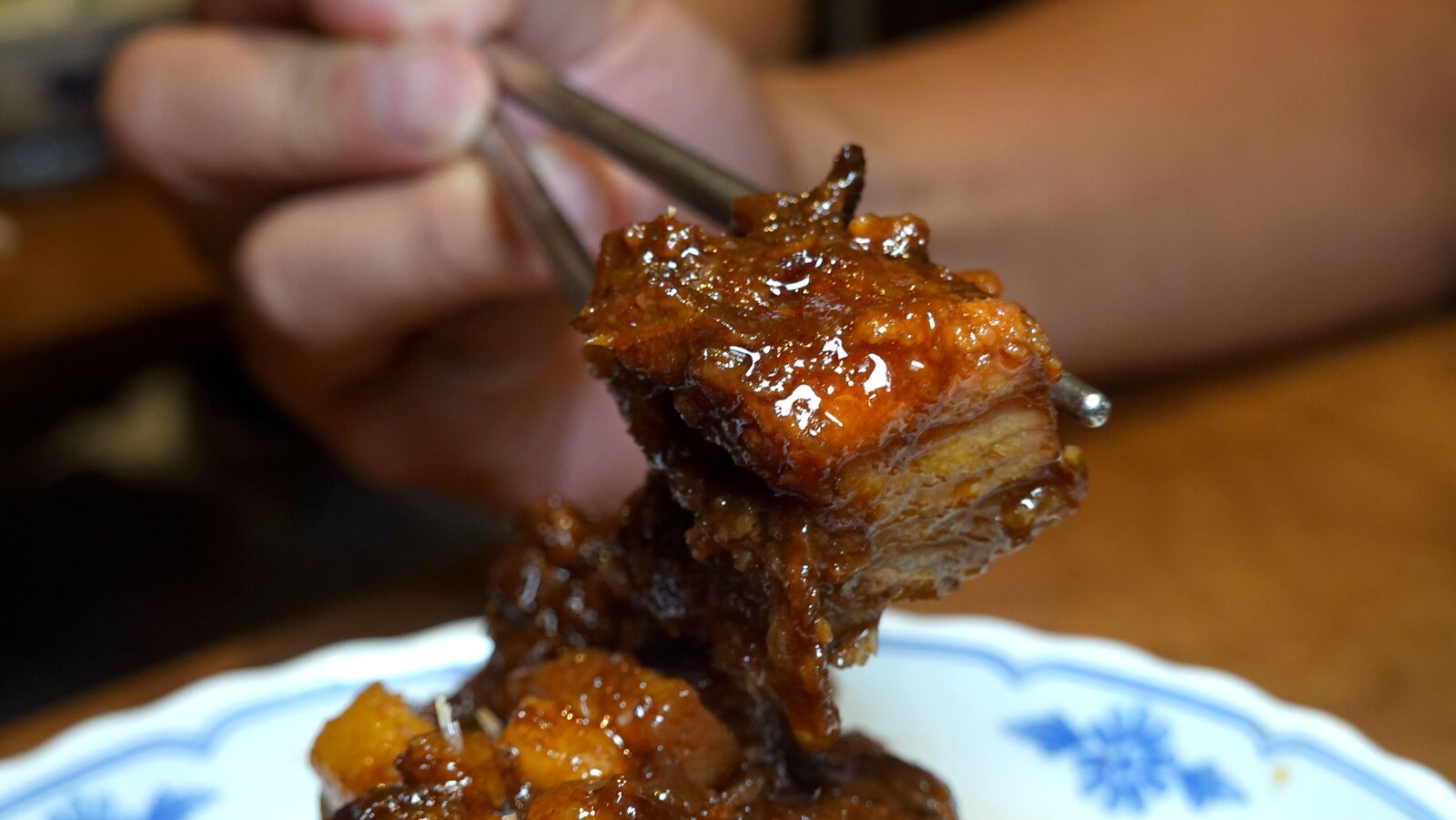 筷子夾起厚切滷大排橫斷面特寫，排骨厚實肉質軟嫩