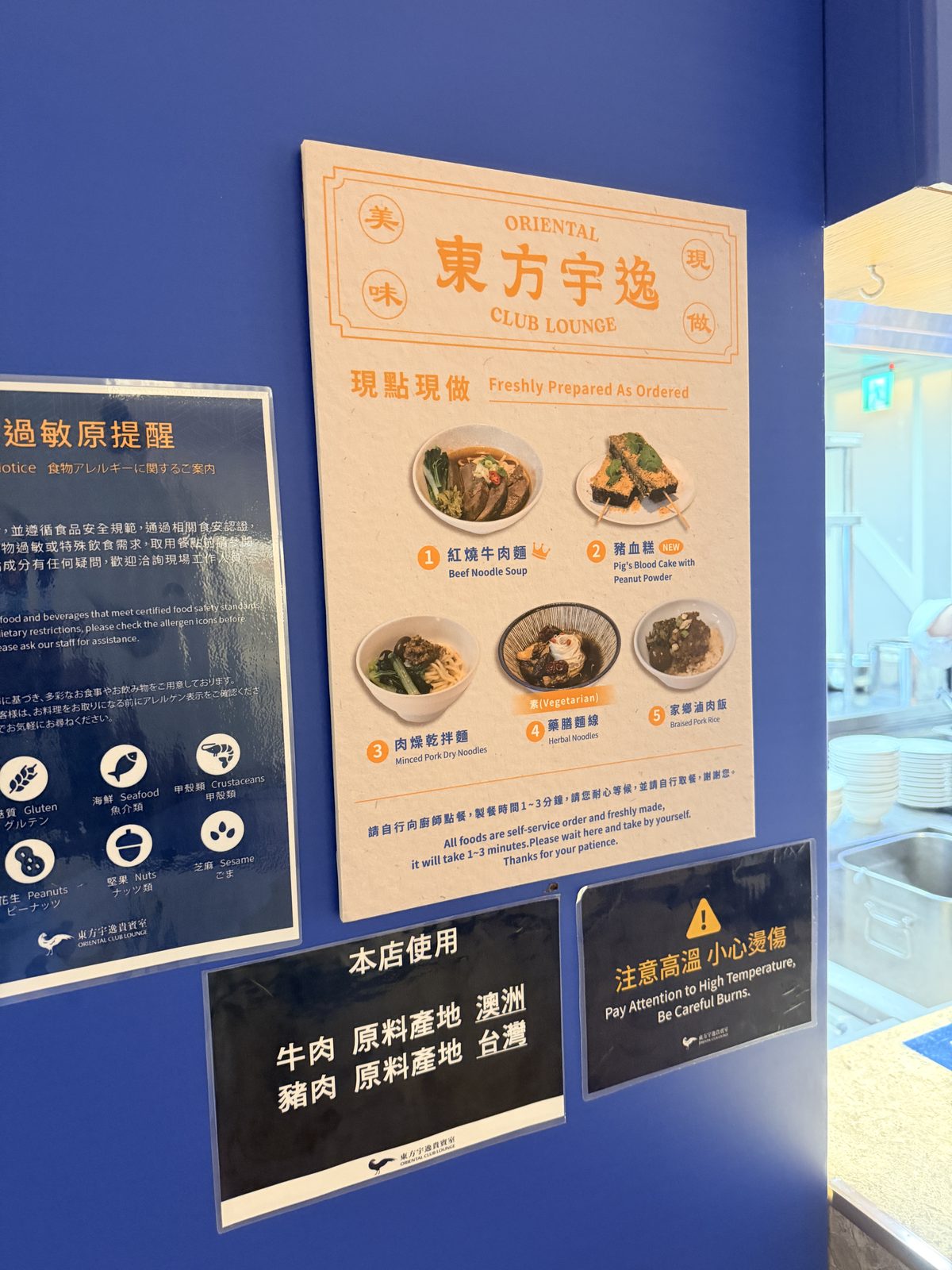 ラウンジの壁にある「現点現做」のメニュー板。隣にアレルゲン表示と牛肉・豚肉の原産地表示