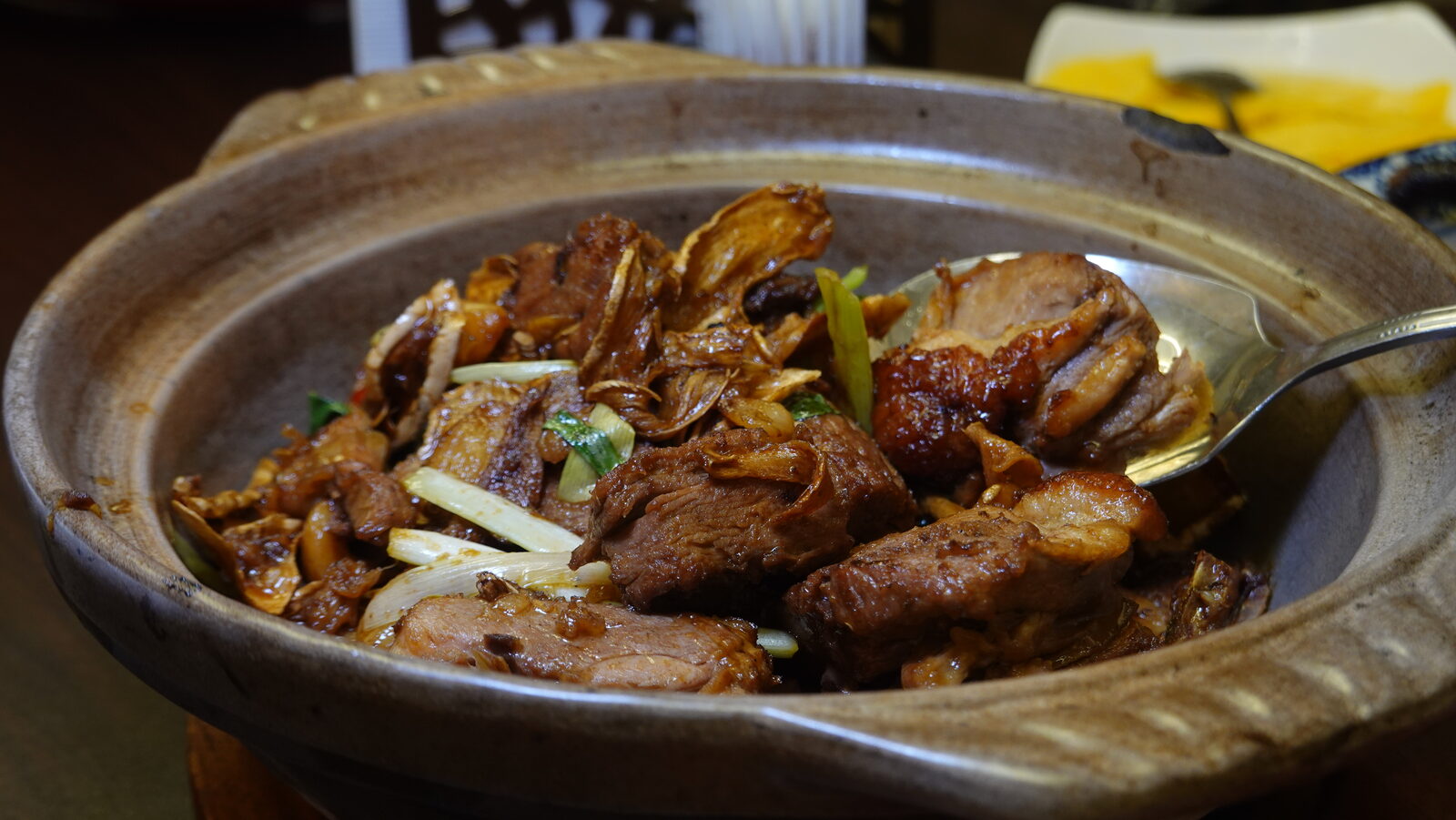 砂鍋燜禽肉，配蒜片與蔥段