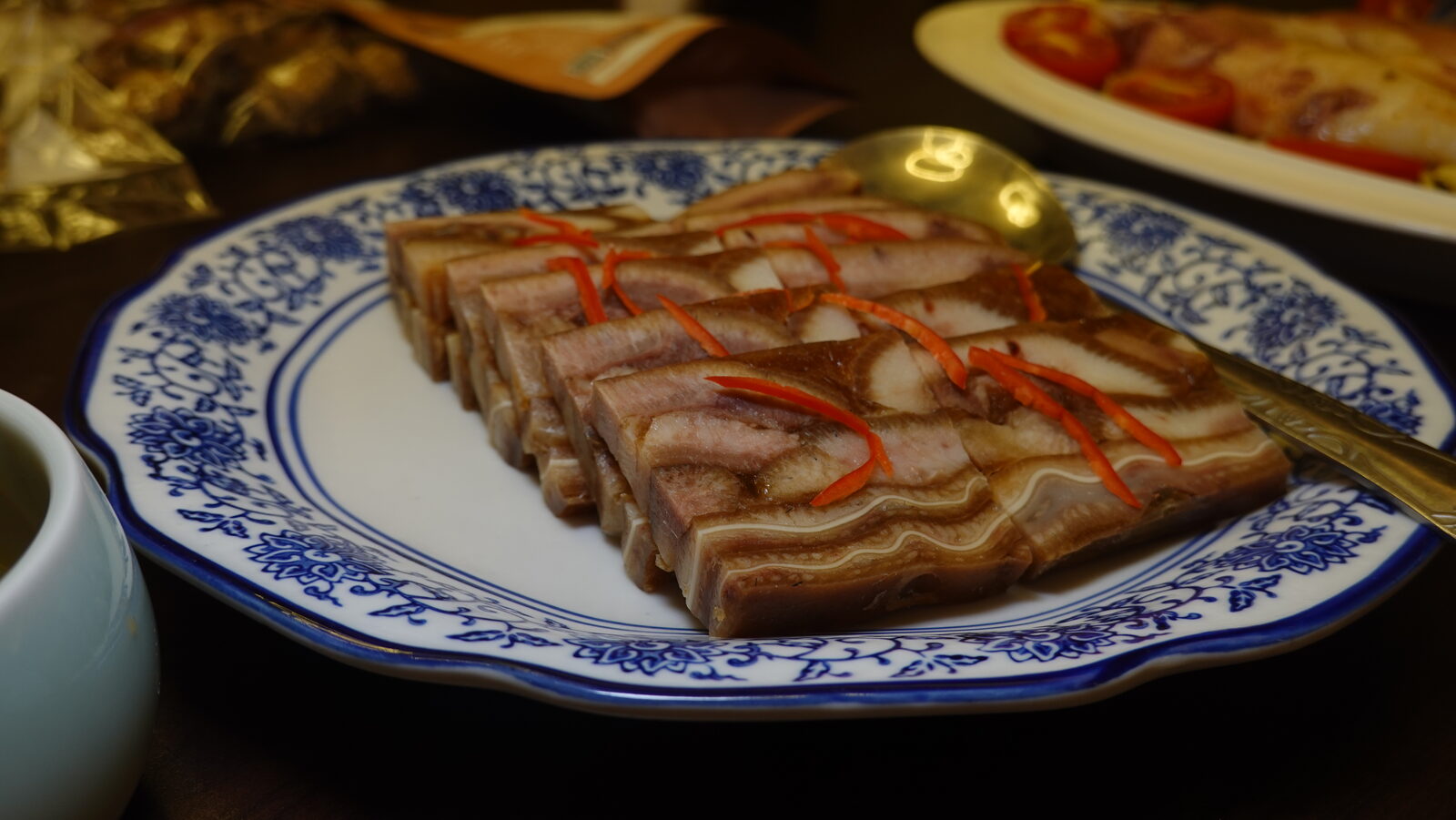青花盤裝切片滷肉凍，上面放辣椒絲