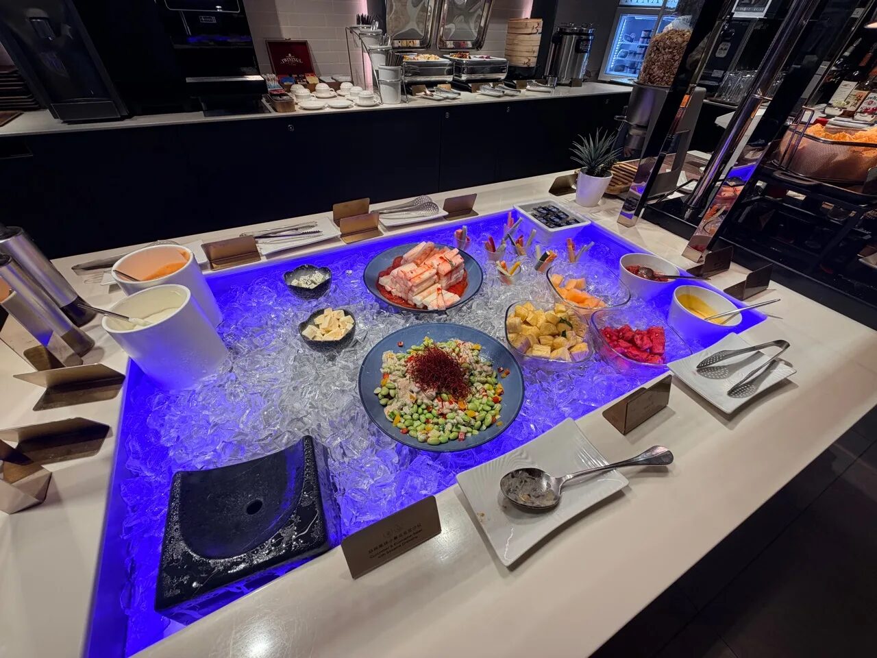スターラックス航空ラウンジの冷菜ビュッフェ台にあるサラダ、野菜スティック、フルーツ