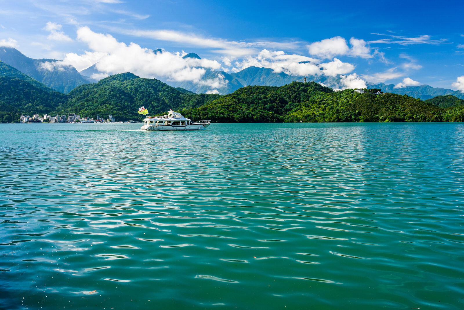日月潭遊湖船行經湖面,後方可見山巒與雲層