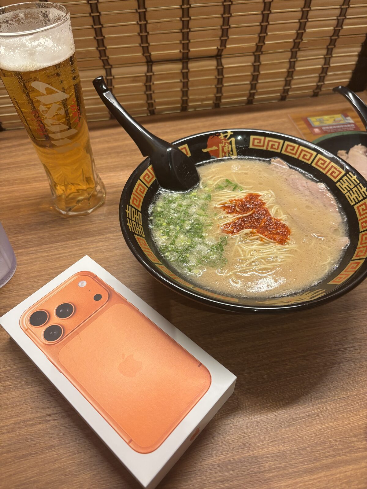 一蘭豚骨拉麵與啤酒，碗中可見叉燒、蔥與赤紅秘製醬汁