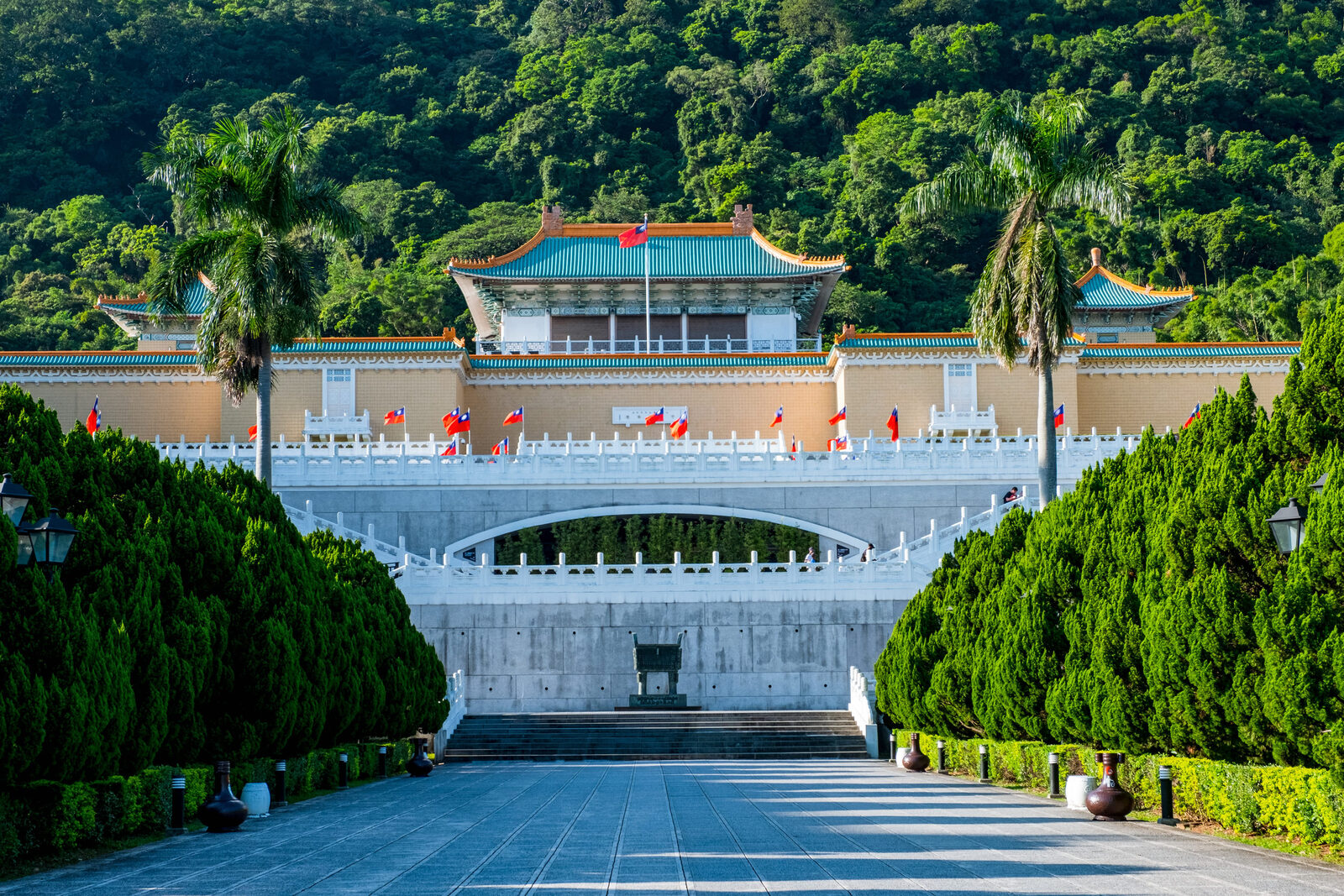 台北國立故宮博物院北部院區正面,階梯、旗幟與山林背景