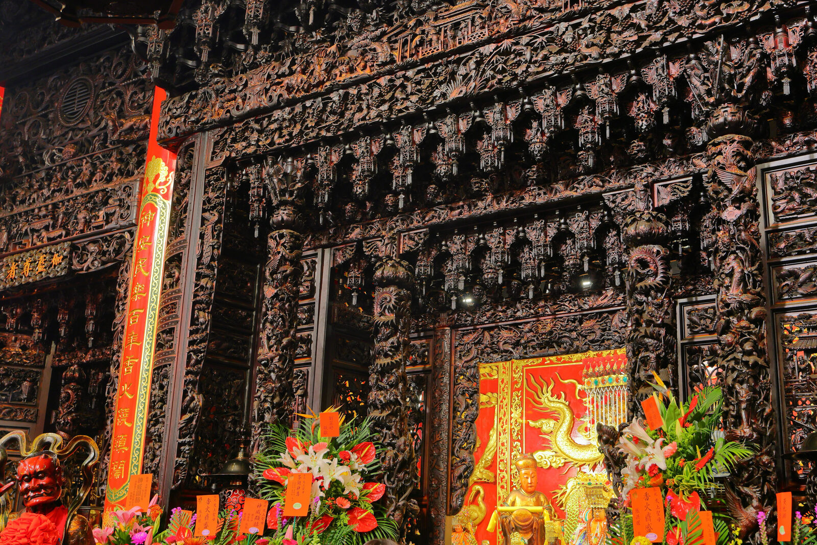 台灣寺廟內部深色木雕神龕、祭祀器物與花供近景
