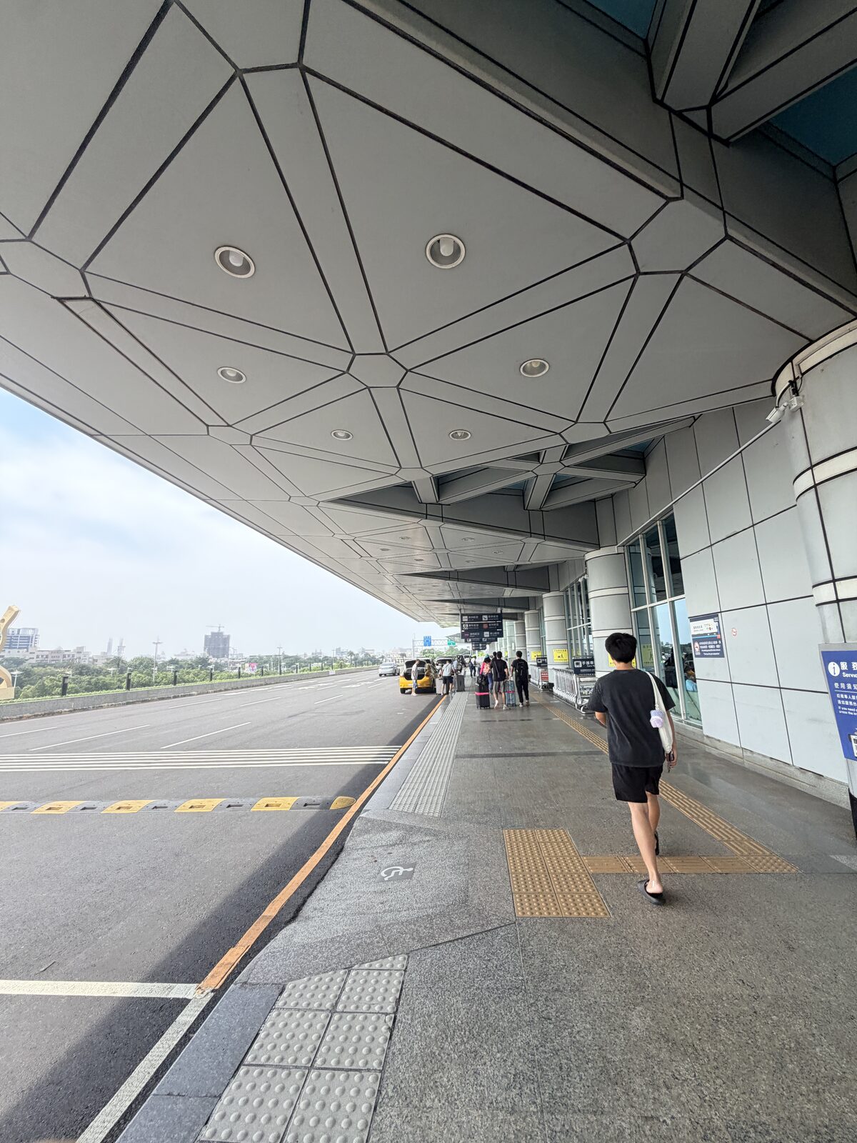 國際航廈出境車道旁的人行道，旅客推著行李往入口走