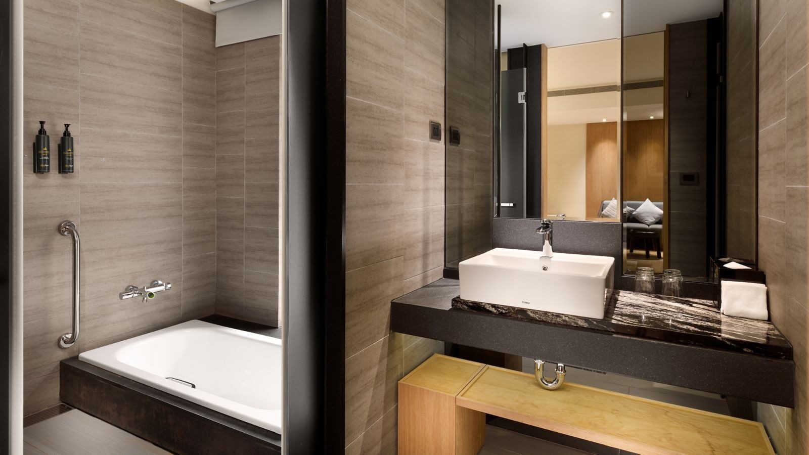 A white bathtub and square sink in a gray stone bathroom