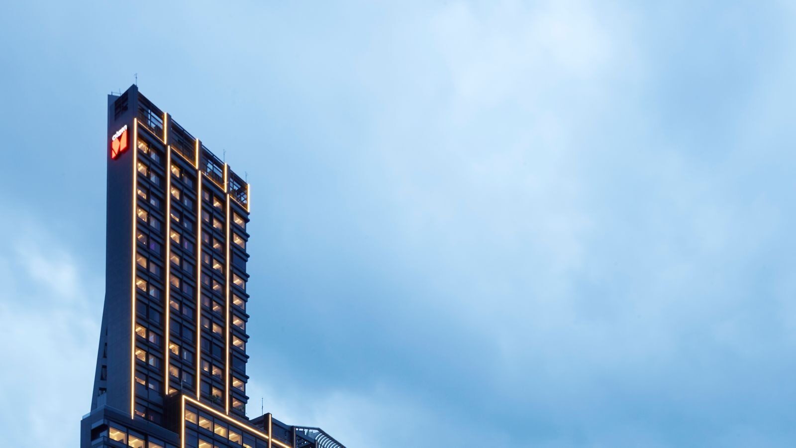 A slender tower under blue sky, topped by a red-and-white citizenM logo