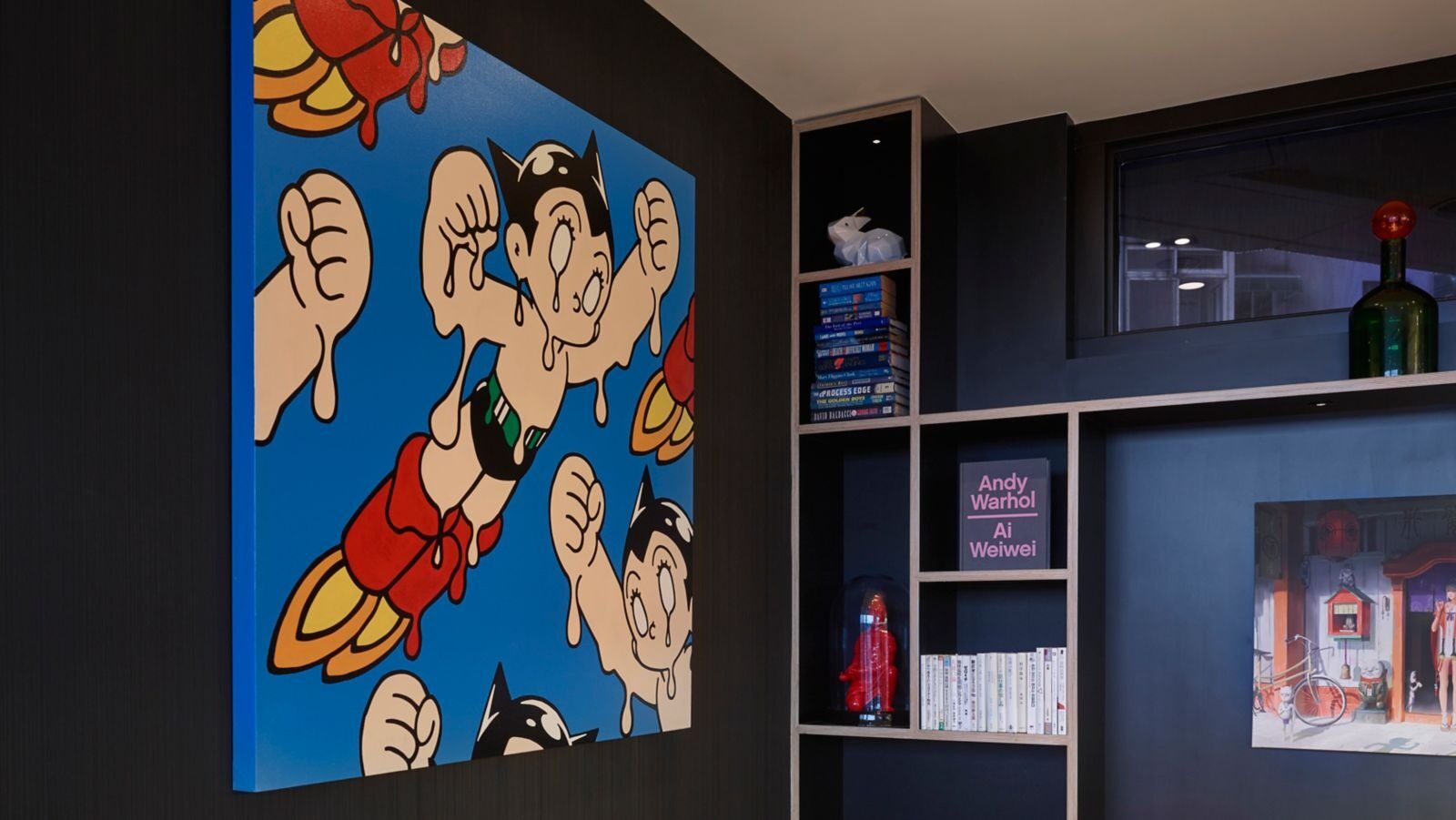 A large pop-art painting of Astro Boy hanging on a black bookcase wall