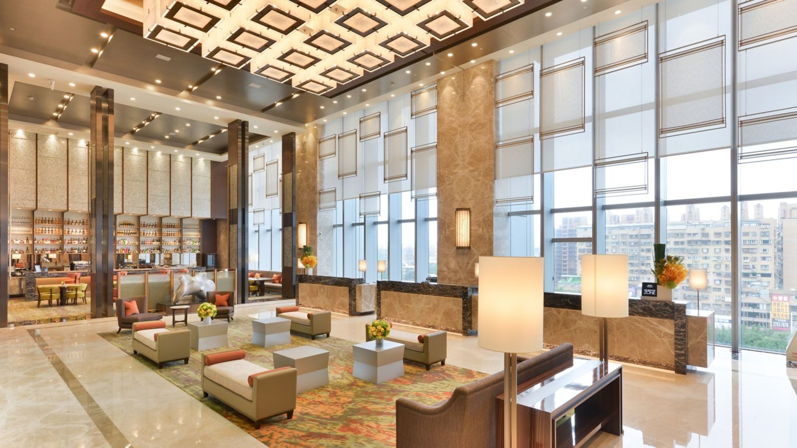Sofa seating and a long row of floor-to-ceiling windows in the high-ceilinged lobby, looking out over Nangang