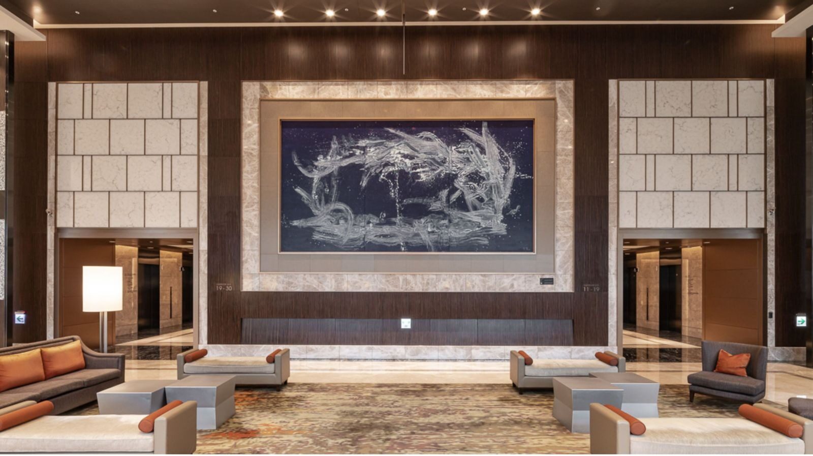 Sofas and coffee tables in the lobby lounge, with a large blue-and-white painting in the center of the wall