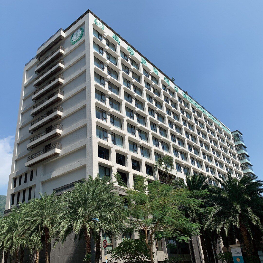 The white guest room tower of Evergreen Resort Hotel (Jiaosi) with palm trees in front