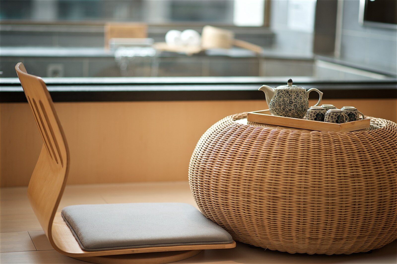Japanese-style floor seats, a rattan stool and a tea set by a guest room window