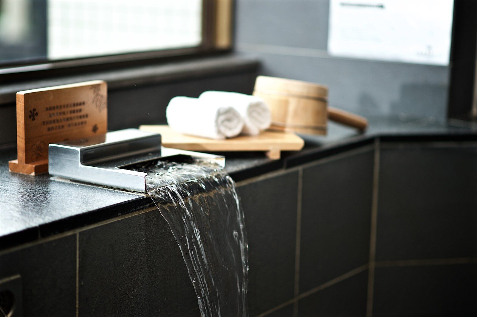 The hot spring spout, a wooden bucket and towels beside a guest room tub