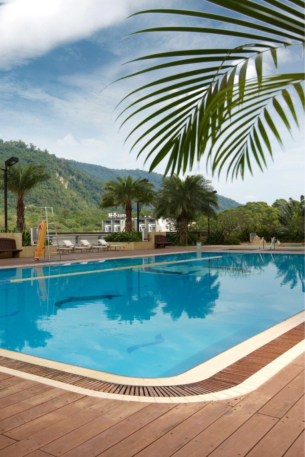 The outdoor pool, a wooden poolside deck and mountains in the distance
