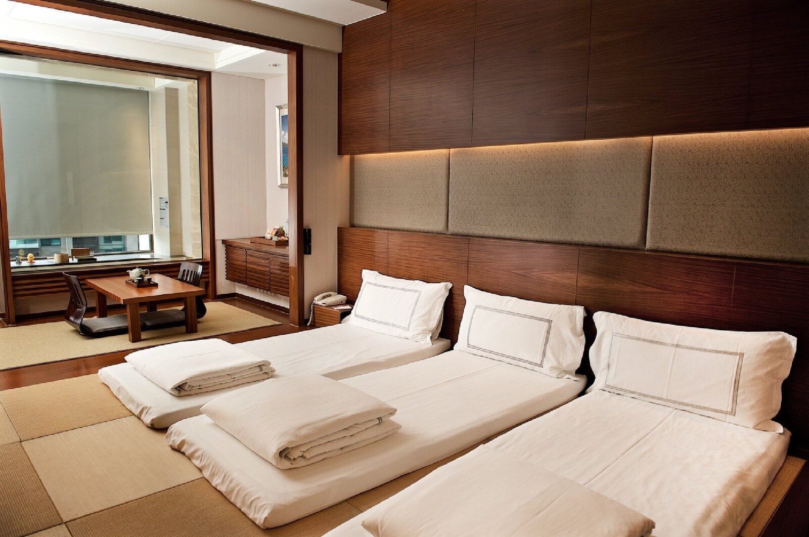Three futons on tatami with a Japanese-style sitting area behind