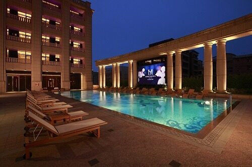 The 4th-floor outdoor pool at Grand Mayfull Hotel Taipei, with poolside Roman columns and a large screen