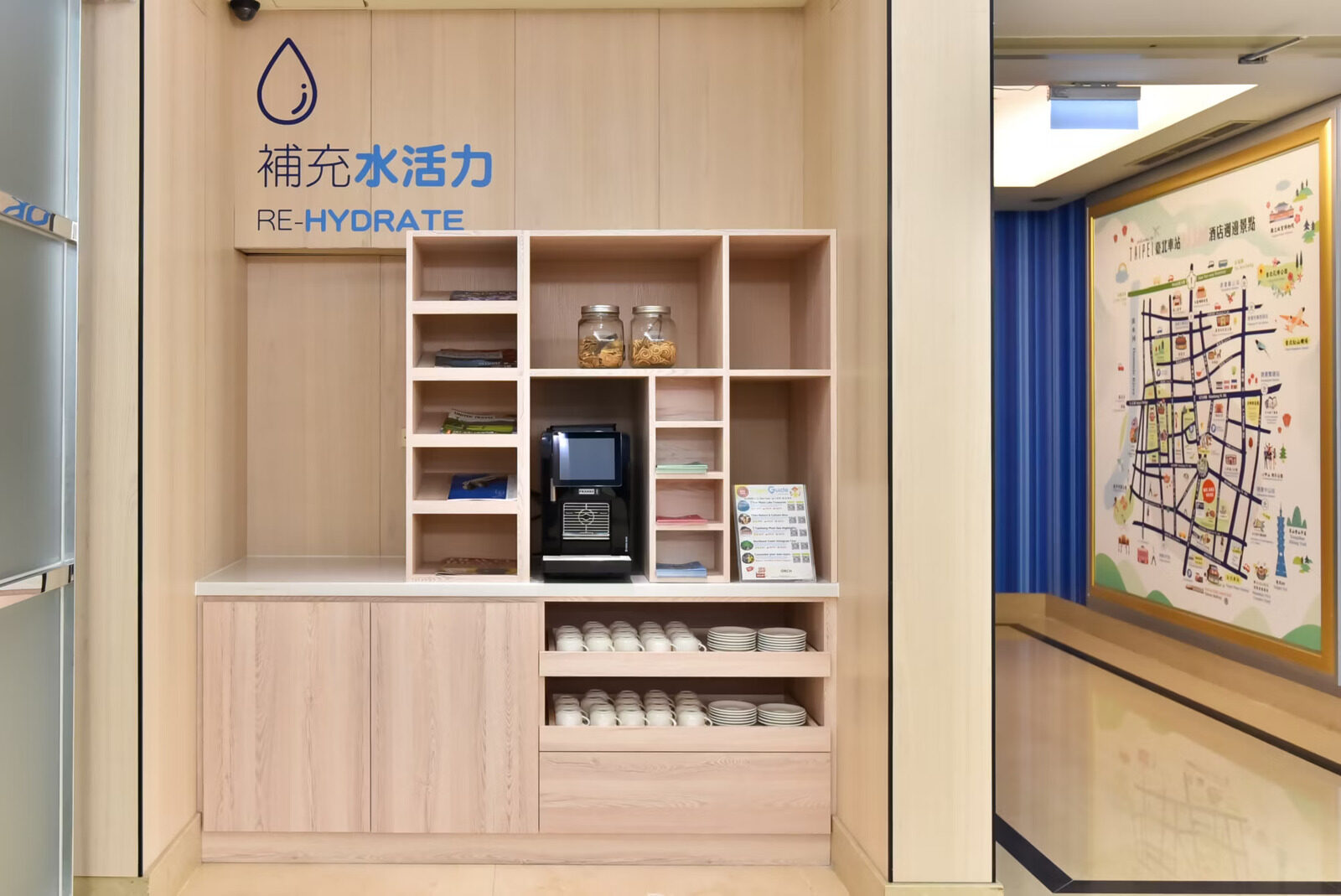 木柜上摆着咖啡机与杯具，旁边墙上挂着周边街区手绘地图