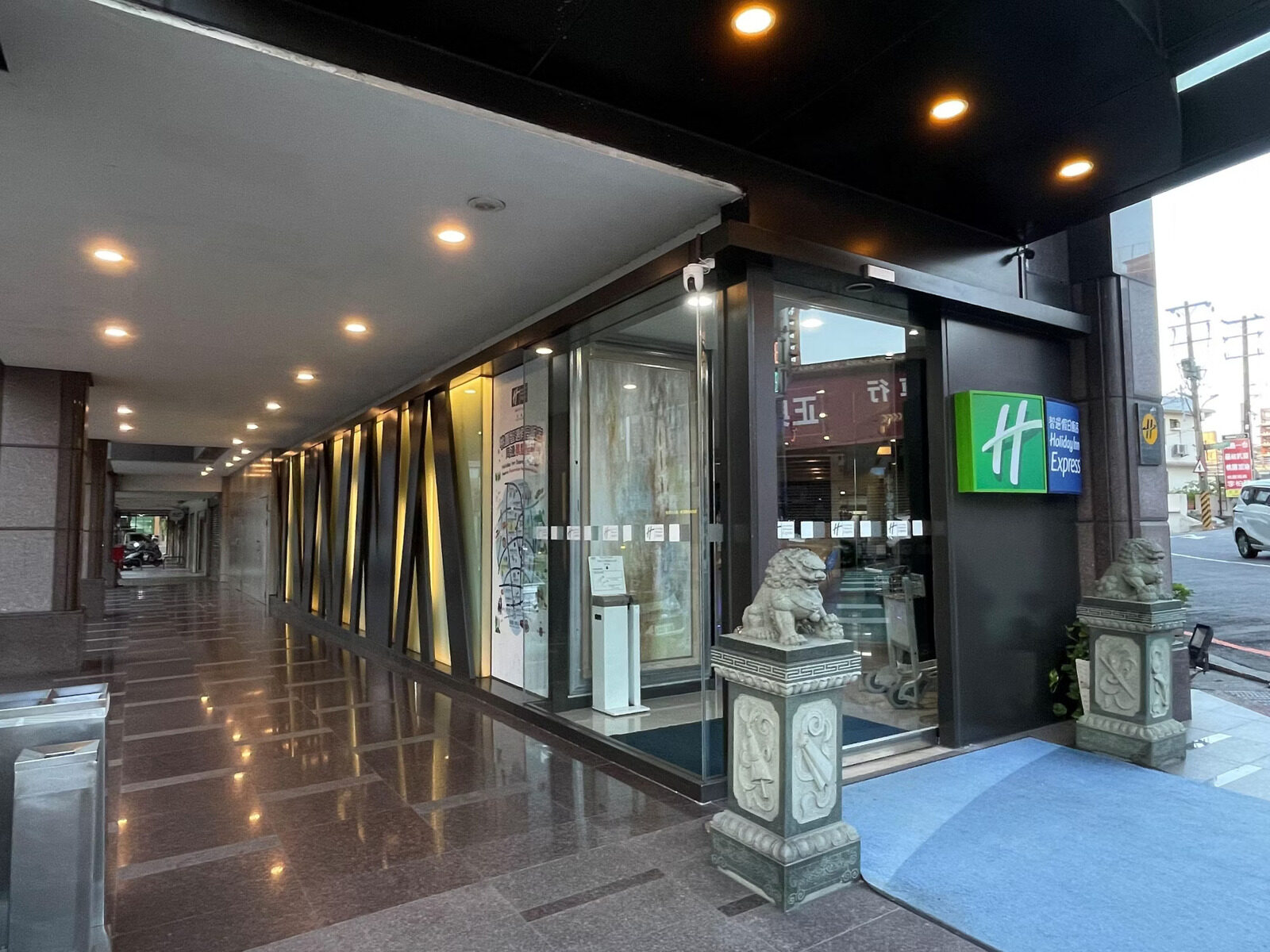 The hotel's glass entrance under an arcade, flanked by a pair of stone lions on a polished stone floor