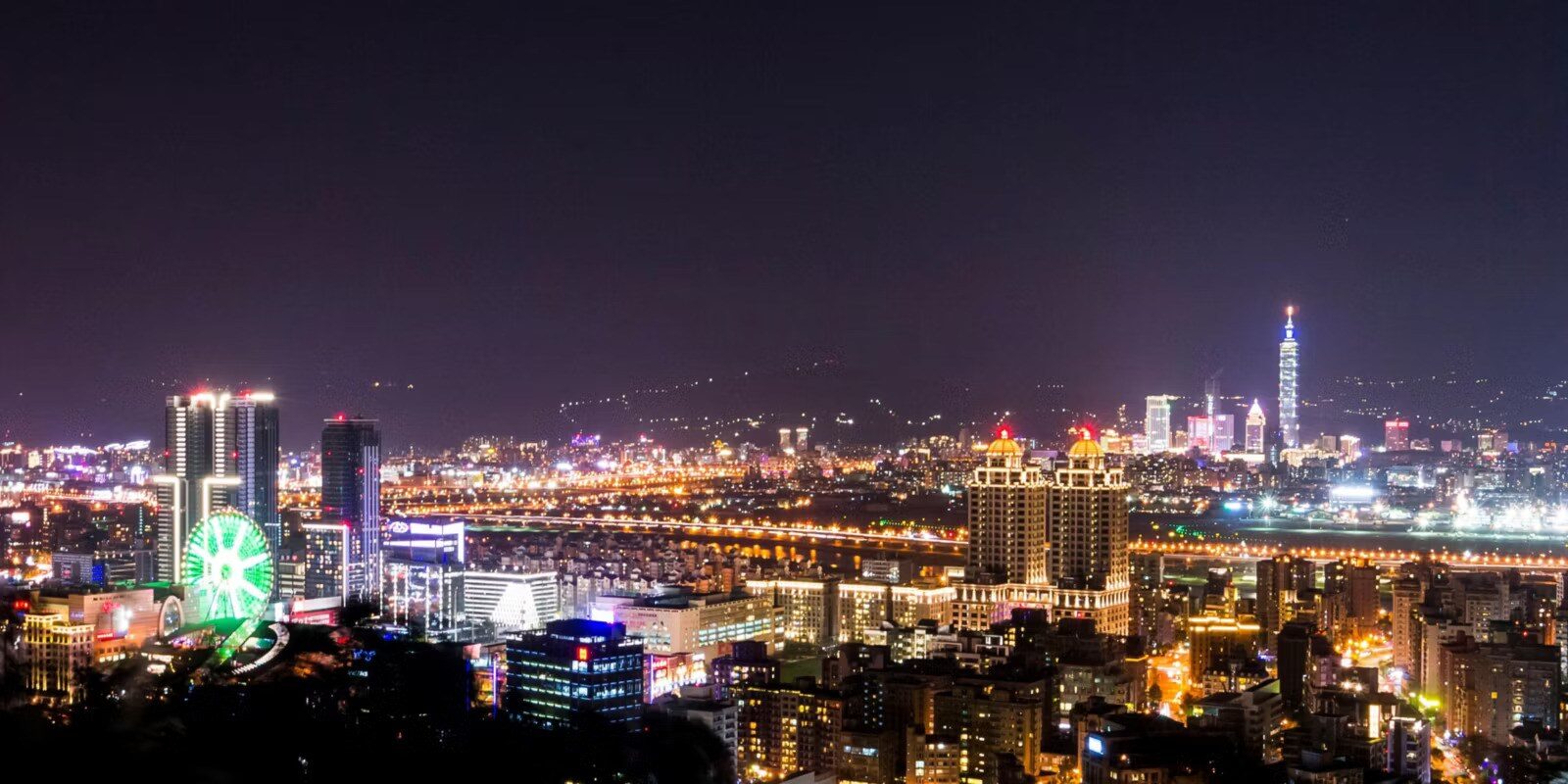 從山上俯瞰的台北夜景，遠處是台北 101 與摩天輪燈光