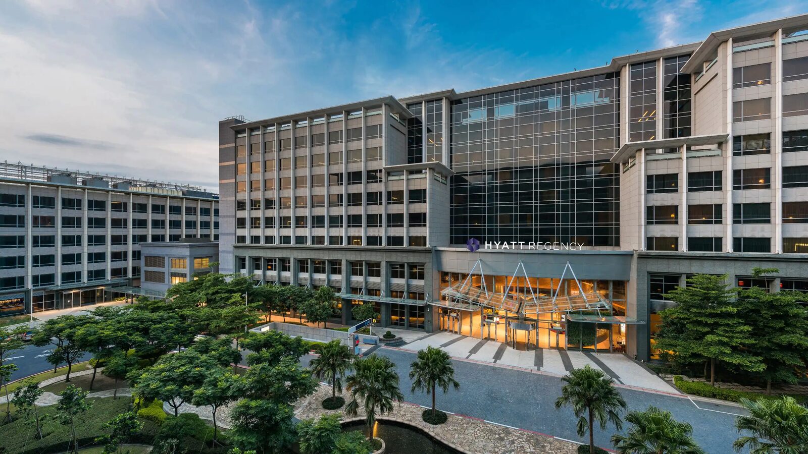 The exterior of Hyatt Regency Taoyuan International Airport, with its glass-canopied entrance and driveway