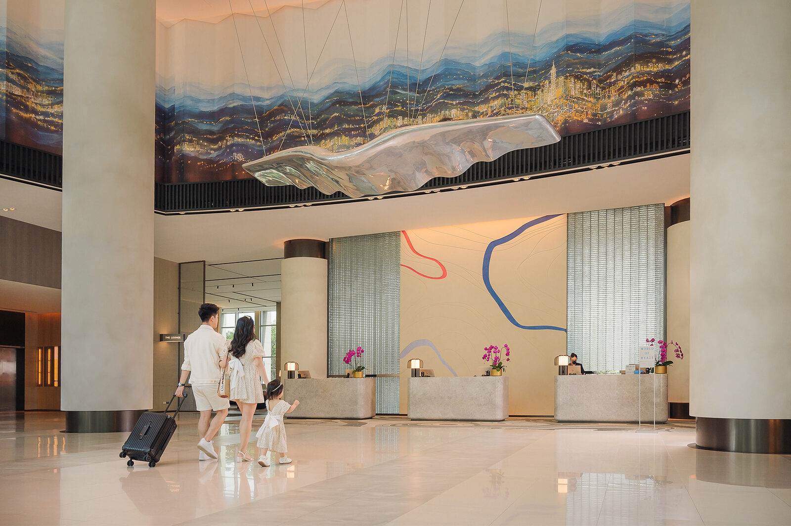 A mountain mural, hanging sculpture and reception desk in the high-ceilinged lobby