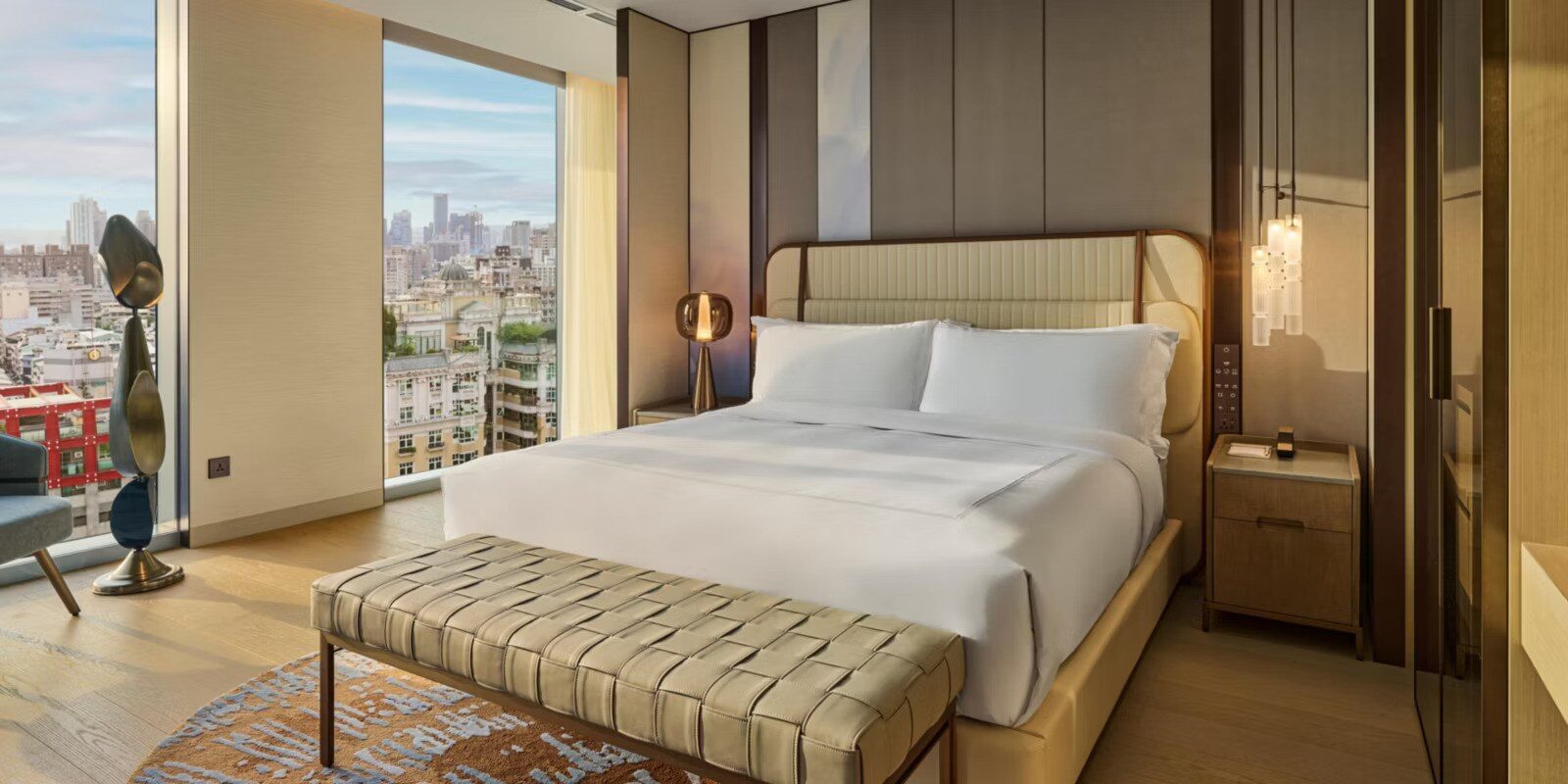 客房的大床、床尾凳與窗外市景