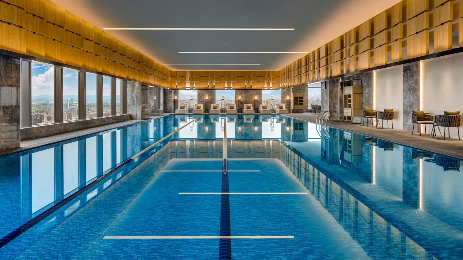 室內溫水泳池的長條水道，一側是整排落地窗