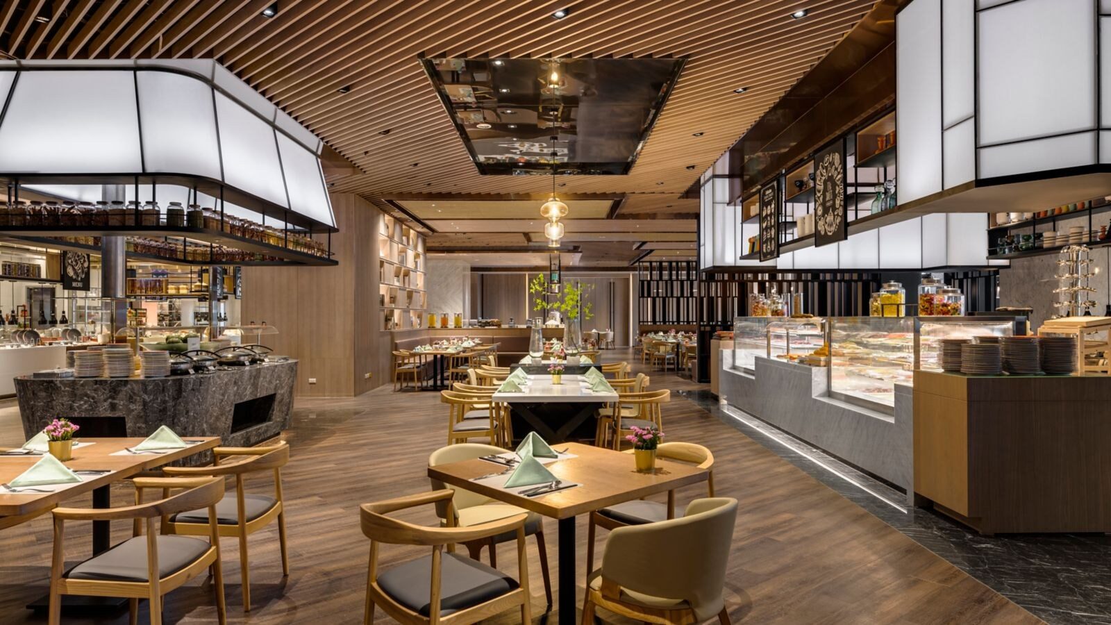 自助餐廳的用餐區，木桌椅後方是明亮的菜色檯與甜點櫃
