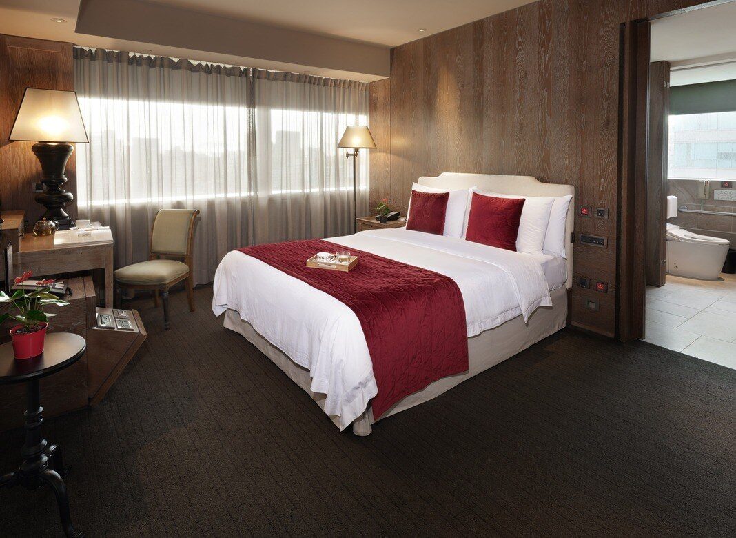 A king bed with a red bed runner and window seating in a room at Palais de Chine Hotel