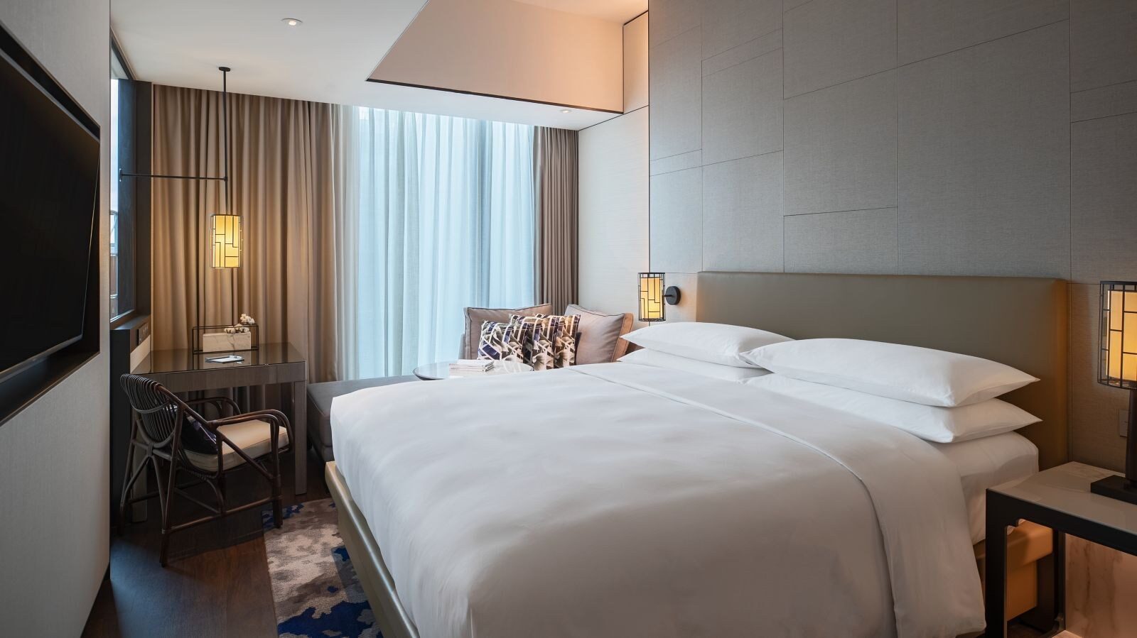 King Club Deluxe 客房的大床、窗邊書桌與中式扶手椅