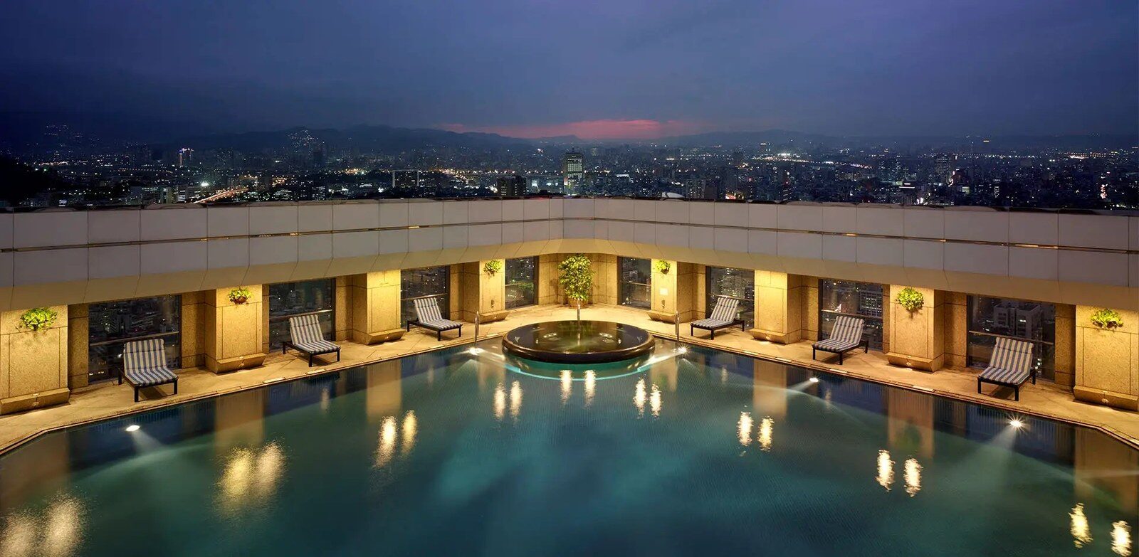 The rooftop outdoor pool at Shangri-La Far Eastern, Taipei with the city at dusk