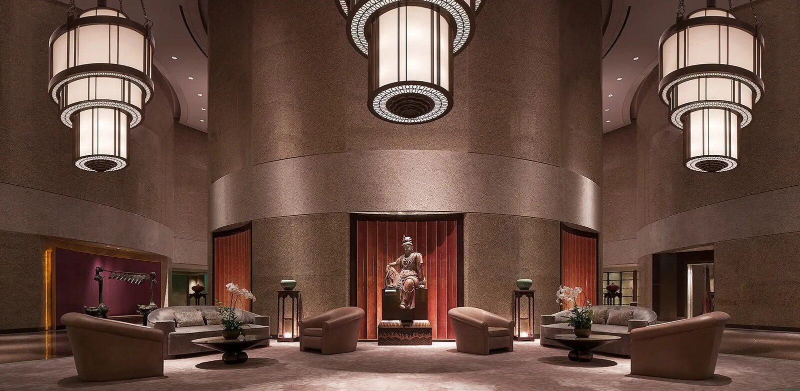 Lantern-style chandeliers, a Buddha statue and sofa seating in the high-ceilinged lobby