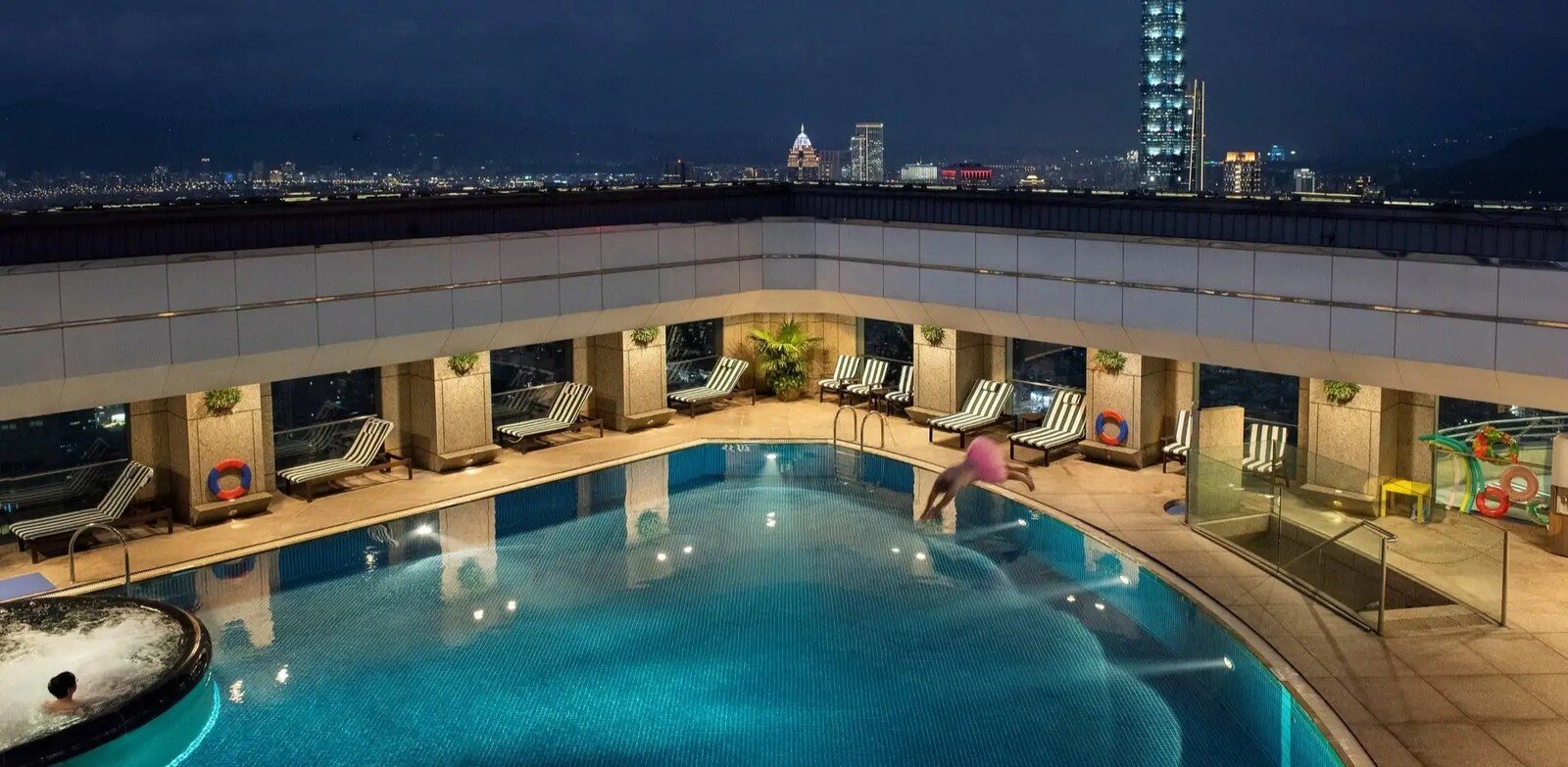 The rooftop pool at night with Taipei 101 in the distance