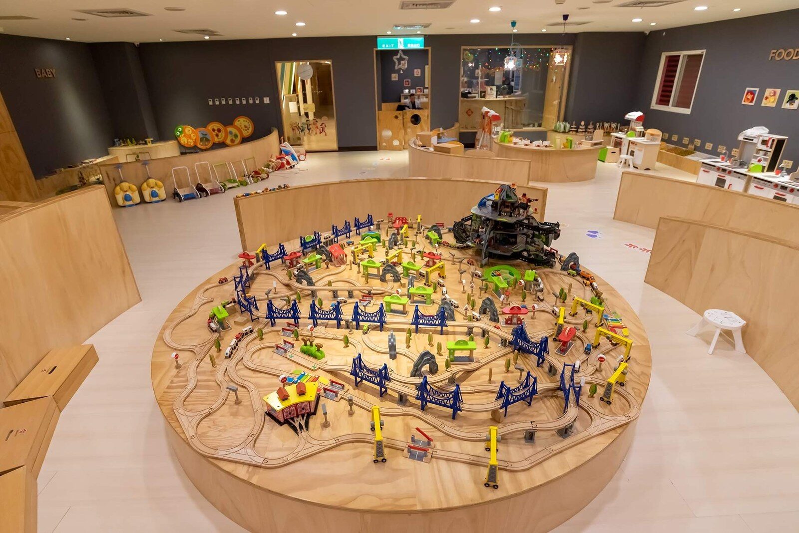 木質裝潢的兒童遊戲區中央鋪滿玩具火車軌道的大桌