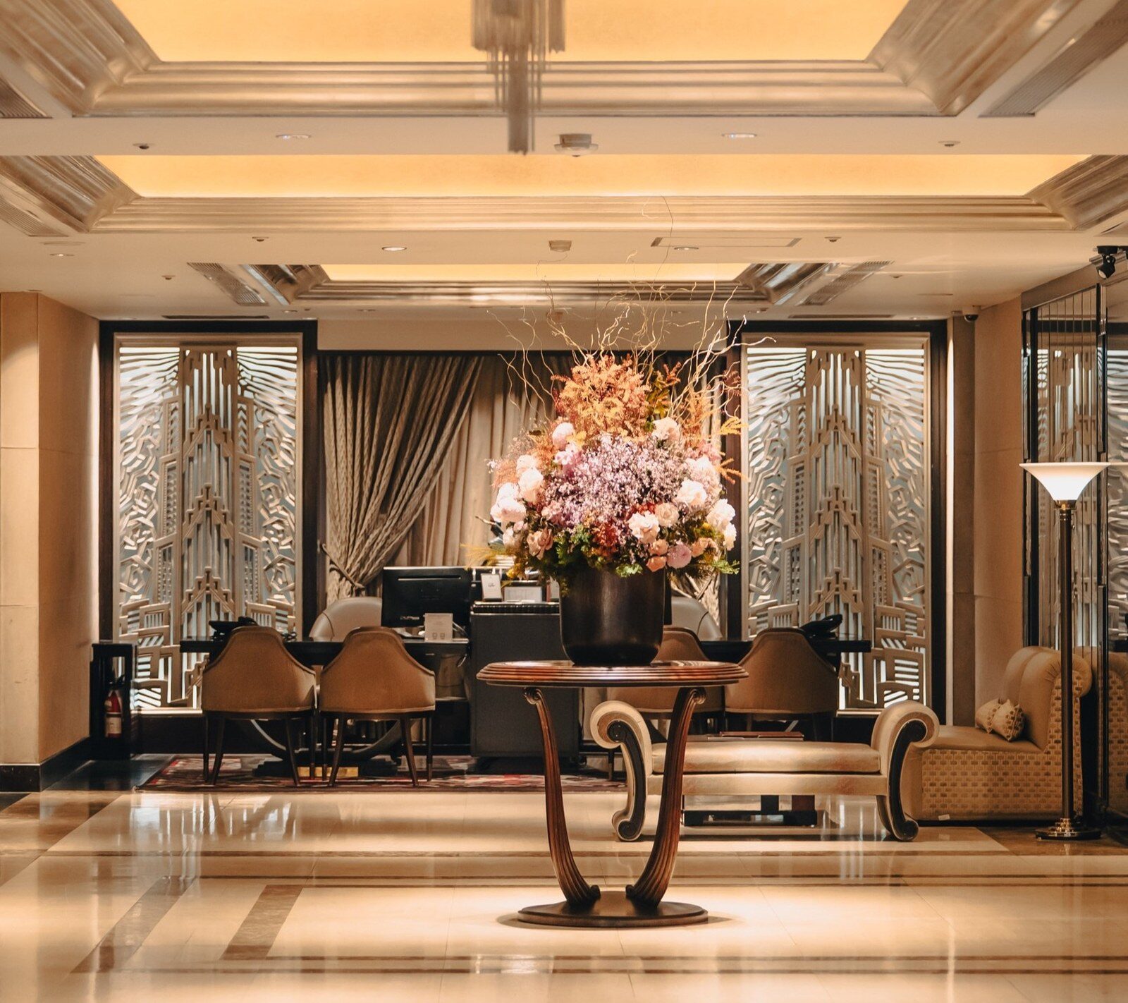 A large floral arrangement, curved table and Art Deco screen in the center of the lobby
