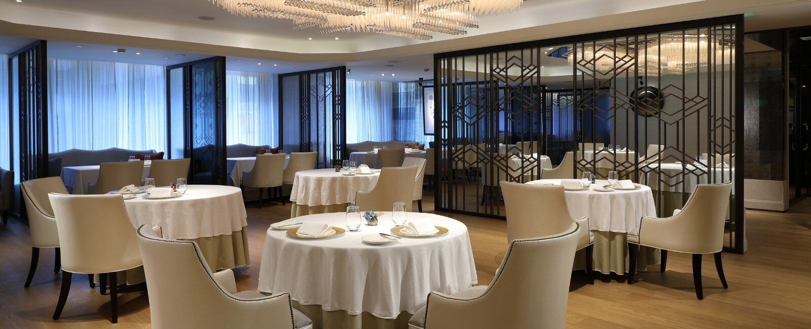 White round tables, beige armchairs and a geometric openwork screen at Paris1930