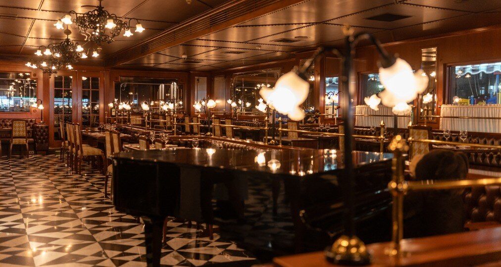 A piano, brass railings and chandeliers at La Brasserie