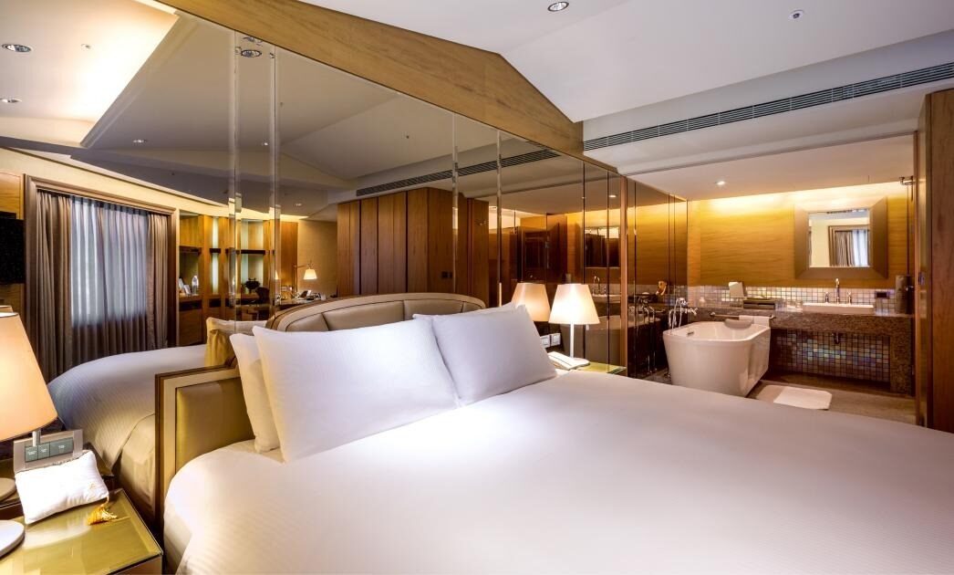 The king bed and open bathtub behind it in a Corner Suite