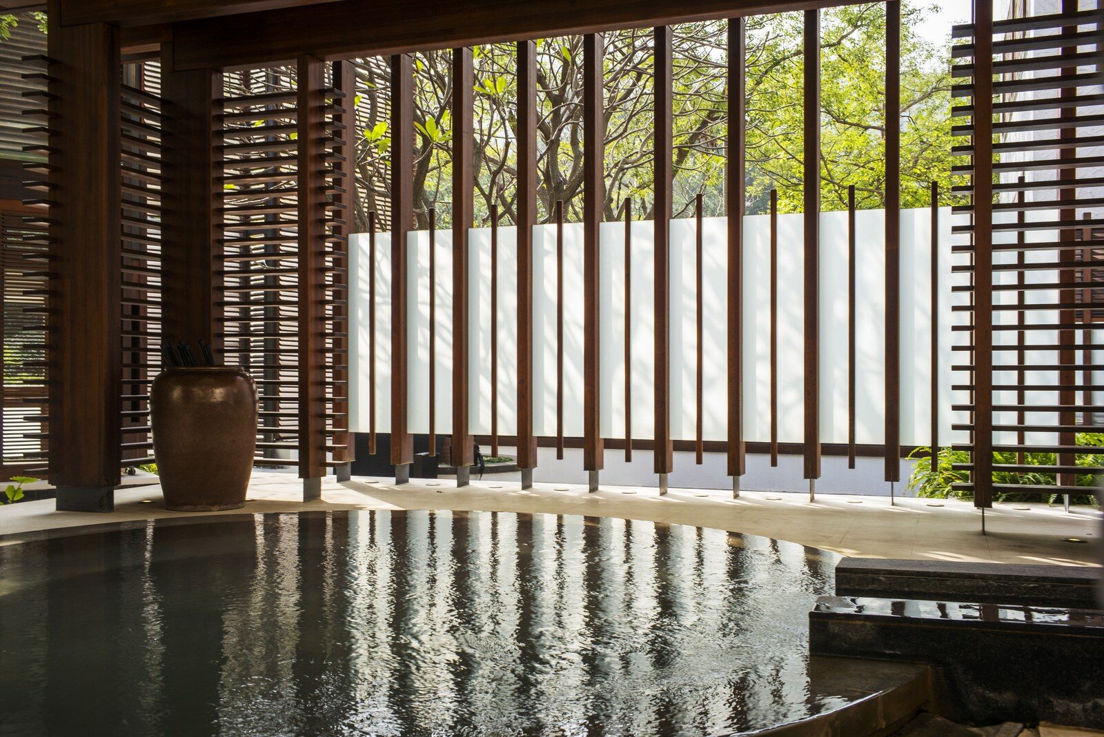 A semi-outdoor public bath surrounded by wooden louvers and white walls