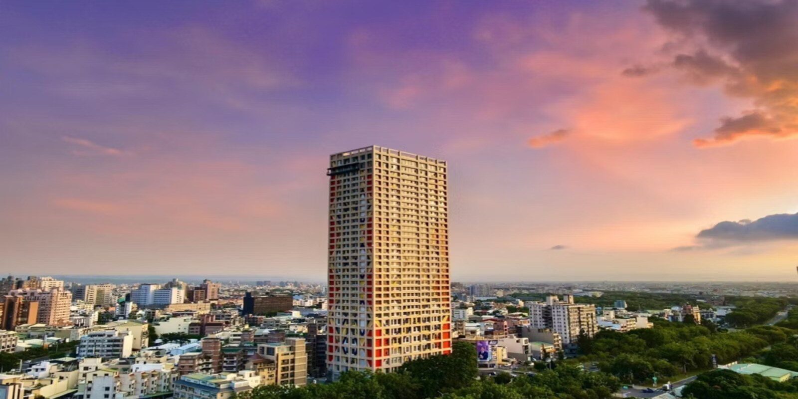 晚霞下的嘉義市區天際線，酒店高樓立在低矮街區與綠樹之間